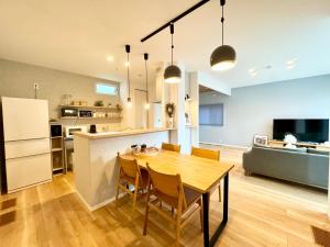 a kitchen and dining room with a wooden table and chairs at Akikawa Koshi 2 プレミアム鉄骨 一棟貸切ヴィラ in Yuge