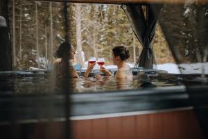 two women sitting in a hot tub drinking wine at Chalet Ankoay - Relaxation Nature & Private Spa in Saint Come