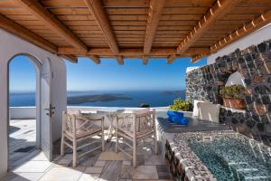 a patio with a table and chairs and a swimming pool at Iliovasilema Suites in Imerovigli