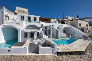 a large white house with a swimming pool at Iliovasilema Suites in Imerovigli