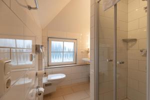 a bathroom with a shower and a toilet and a window at Gasper Business & Garden Hotel in Raunheim