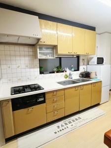 a kitchen with yellow cabinets and a stove top oven at Koyasui Guesthouse for Groups Easy Access to Yokohama & Shin-Yokohama in Yokohama