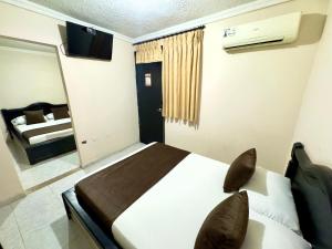 a bedroom with a bed and a mirror and a television at Hotel Buenavista Valledupar in Valledupar