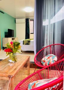 a living room with two red chairs and a wooden table at Airport Pamatai Studio in Faaa