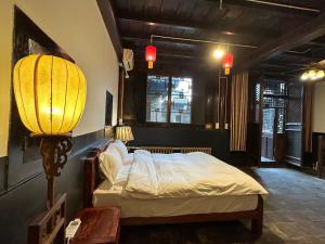 a bedroom with a bed with a lamp and a table at Pingyao Yide Hotel in Pingyao