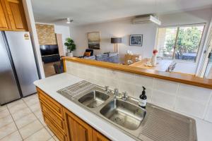 a kitchen with a stainless steel sink and a living room at Ibis Rest Beach House in Geographe