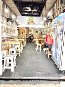 a dining room with wooden tables and white stools at J&T House And Friends in Ban Khlong Nam Ron