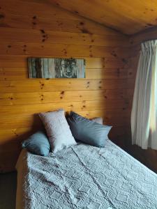 a bedroom with a bed with a wooden wall at Steve's Cozy Retreat in Taupo