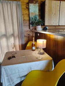 a table with two glasses and a lamp and yellow chairs at Steve's Cozy Retreat in Taupo