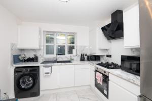 a kitchen with white cabinets and a washer and dryer at Elegant and Modern Apartment 3 Double Bedroom Near City Centre Entire House Parking in Manchester