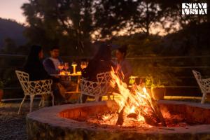a group of people sitting around a fire pit at Sirmour Baag by Vaana - A part of StayVista in Nahna