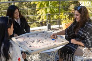 a group of women playing a game on a table at Sirmour Baag by Vaana - A part of StayVista in Nahna