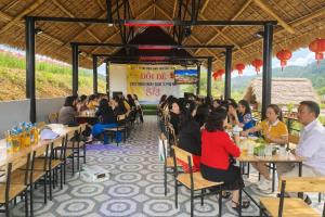 a group of people sitting at tables in a restaurant at Đồi Dẻ Eco HomeStay in Bố Trạch