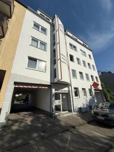 a white building with a car parked in front of it at BoardingHouse - Studios & Apartments in Kassel