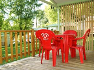 two red chairs and a table on a deck at Chalet avec terrasse - 2 pers. - API-1-52-1592 in Saint-Girons