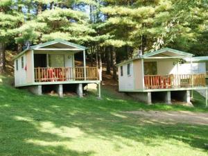 two cottages with decks in a yard with trees at Chalet avec terrasse - 2 pers. - API-1-52-1592 in Saint-Girons