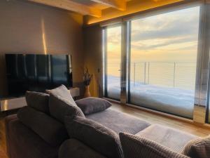 a living room with a couch and a large window at Yunagi 夕凪プライベートサウナ付ヴィラオーシャンフロントの絶景宿 夕日とサウナを満喫海と夕日に包まれる贅沢空間 in Mōrai