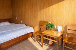 a bedroom with a bed and a desk and a table with a chair at Đồi Dẻ Eco HomeStay in Bố Trạch