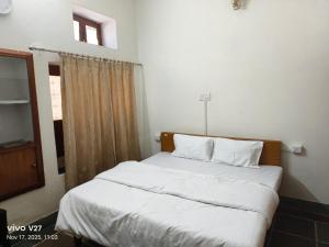 a bedroom with a bed with white sheets and a window at Riddhi Guest House in Udaipur