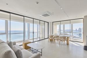 a living room with a couch and tables and windows at Palatium Haeundae by SONO Felice in Busan