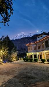 a large building with a snow covered mountain in the background at Hikal Guest House in Gilgit