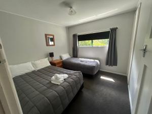 a bedroom with a bed and a ottoman and a window at Kiwi Park Motels in Murchison