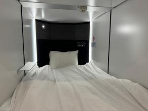 a white bed in a room with a mirror at Capsule Hotel Suzumoriya in Tokyo