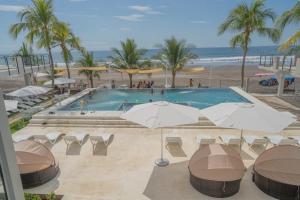 a pool with chairs and umbrellas and the beach at Coco Blue a New Beach Resort in La Libertad +24 photos