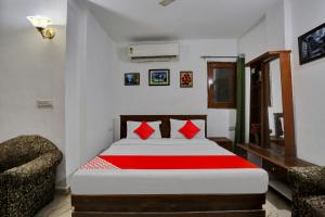 a bedroom with a bed with red pillows and a chair at Hotel O by OYO TSA in New Delhi