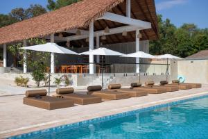 a row of lounge chairs and umbrellas next to a swimming pool at Le Baoli Koh Rong in Phumĭ Kaôh Rŏng +34 photos