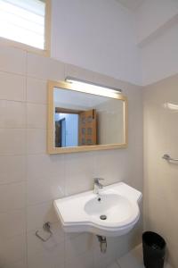 a white bathroom with a sink and a mirror at Thaayar Homestay by Highpoint in Tiruchirappalli +13 photos
