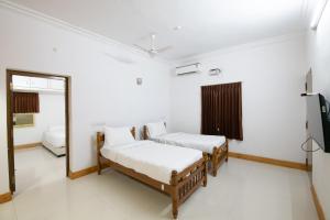 a room with two beds and a television at Thaayar Homestay by Highpoint in Tiruchirappalli