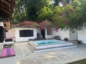 a swimming pool in a yard with pink flowers at Cinnamon lodge rooms in Koggala