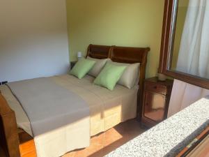a bedroom with a bed with green pillows and a window at Casa Vacanze a Luino - Casa di Adele in Luino