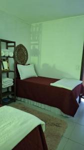 a bedroom with two beds and a book shelf at Morada Héstia in Imbé
