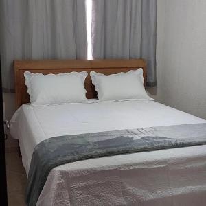 a bed with white sheets and pillows in a bedroom at Hospedagem cama e café in Domingos Martins