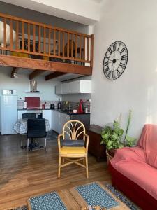 a living room with a red couch and a clock on a wall at Appartement Hyper Centre in Limoges +8 photos