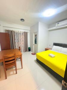a bedroom with a yellow bed and a wooden table at Guest hotel Palestina Pili in Pili