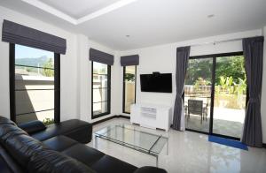 een woonkamer met een bank en een flatscreen-tv bij Baan Ping Tara Tropical Private Pool Villa in Ao Nang Beach