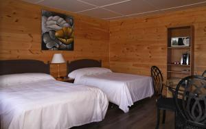 a bedroom with two beds and a table and a painting at Motel 149 in Mont-Tremblant +9 photos