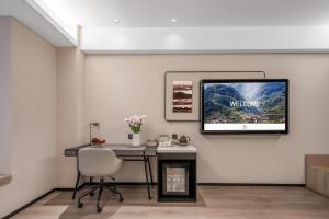 a room with a desk and a television on a wall at 成都高新天府三街亚朵酒店 in Chengdu