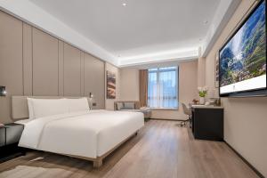 a bedroom with a large white bed and a flat screen tv at 成都高新天府三街亚朵酒店 in Chengdu