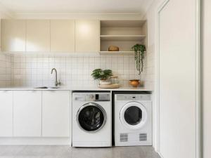 a white laundry room with a washer and dryer at Capri Garden Stay in Gold Coast