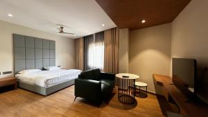 a bedroom with a bed and a chair and a television at Cloud Nine Hotel in Kottayam