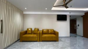 a yellow couch in a room with a ceiling fan at Cloud Nine Hotel in Kottayam