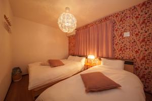 two beds in a small room with a chandelier at LilyHouse in Beppu