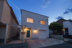 a white house with a garage in front of it at LilyHouse in Beppu