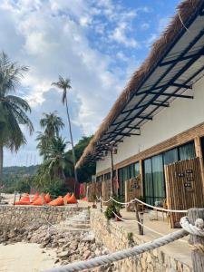 a resort with a palm tree and a building at Malila Sea Breeze Hostel in Ko Tao