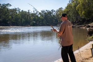 a man standing on the beach holding a fishing rod at Tasman Holiday Parks - Merool on the Murray in Echuca +16 photos