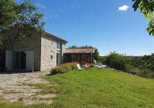 a stone house with two chairs in the yard at Le Trible in Labeaume